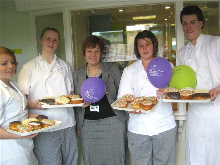 Jenny Worsdale with students holding doughnuts